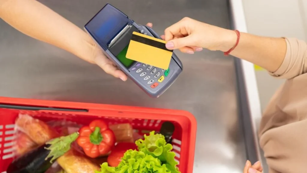 Kartu E-Money Bisa Untuk Apa Saja? Fungsi & Keuntungan Penggunaannya Transaksi di kasir menggunakan kartu e-money, menggambarkan fungsi kartu e-money untuk belanja kebutuhan sehari-hari.