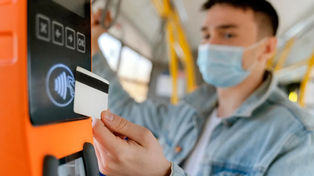 Kartu E-Money Bisa Untuk Apa Saja? Fungsi & Keuntungan Penggunaannya Seseorang melakukan tap-in di gerbang stasiun, menyoroti fungsi kartu e-money untuk transportasi umum seperti KRL dan MRT.